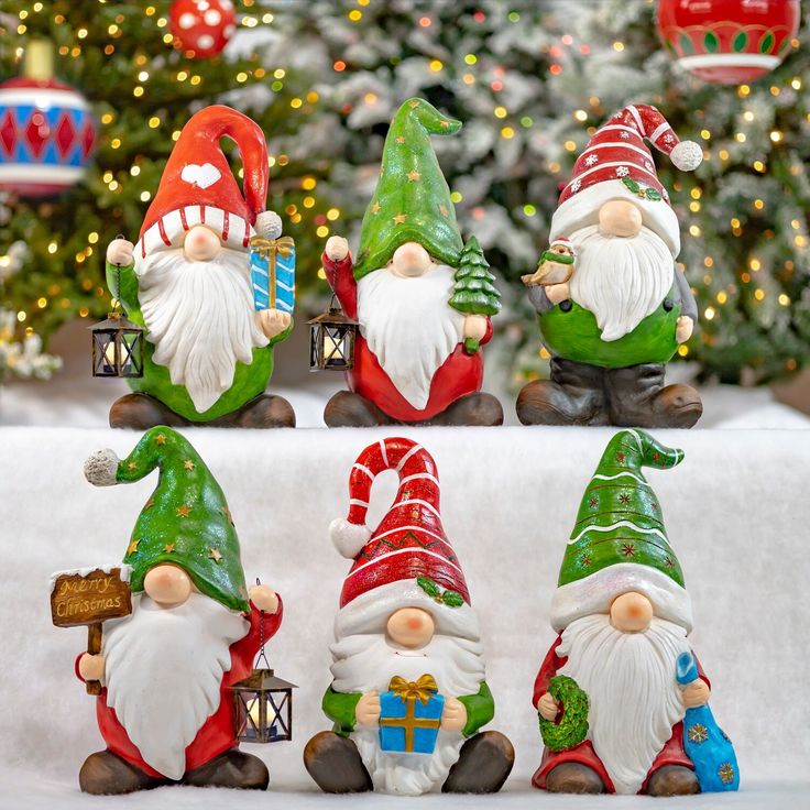 christmas gnomes are sitting in front of a christmas tree