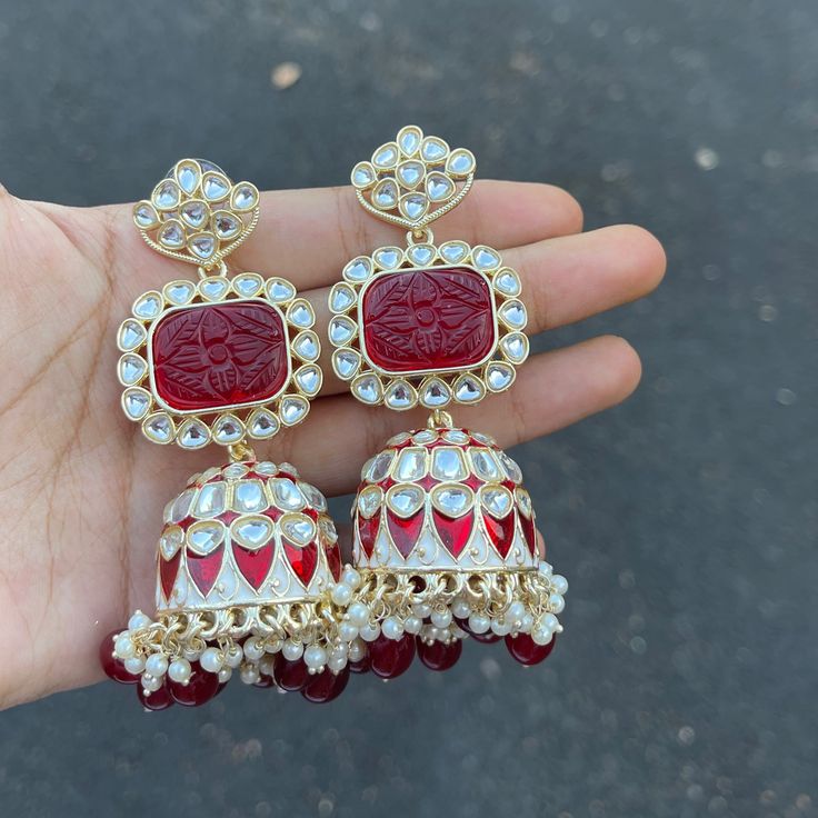 The Maroon Jiya Earrings are unique, and lightweight Jhumkas with Kundan, Meenakari and Gold-Plating on beautiful hydro beads. Specifications Materials used: Kundan, Meenakari, hydro beads, Gold Plating Weight: 41 g Height: 3.5 inches At Romikas, we pride ourselves on the craftsmanship and high quality of our jewelry, designed to enhance your natural beauty. Please contact us with any questions. Red Jhumkas Earrings, Traditional Meenakari Dangle Jhumkas, Traditional Bridal Earrings With Cutdana For Gifts, Fusion Style Kundan Dangle Jhumkas, Kundan Fusion Dangle Jhumkas, Fusion Kundan Jhumkas With Meenakari, Fusion Style Kundan Jhumkas With Meenakari, Temple Jewelry Cutdana Jhumkas As Gift, Red Temple Jewelry Earrings For Navratri