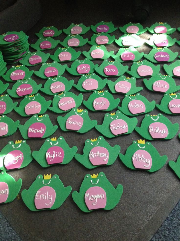 a table topped with lots of green and pink paper cut outs covered in name tags