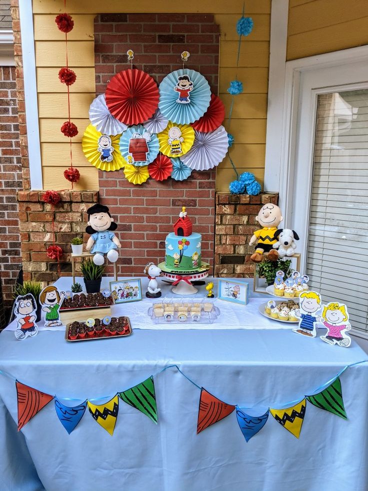 a blue table topped with cake and cupcakes next to a red brick wall