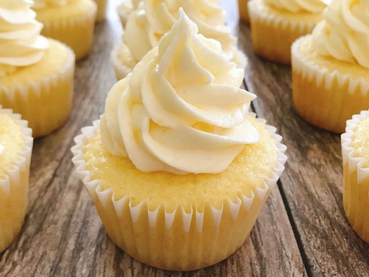 cupcakes with white frosting sitting on a wooden table