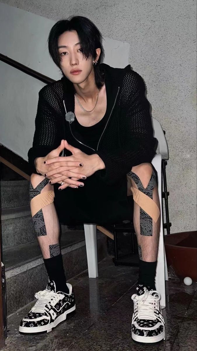 a man sitting on top of a white chair next to a stair case with his hands crossed