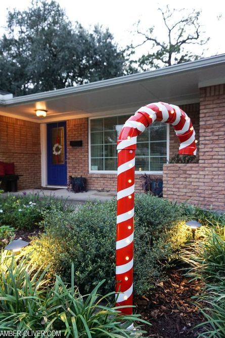 a large candy cane in front of a house with christmas lights on it's side