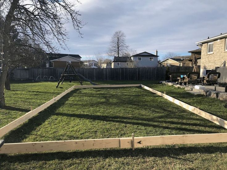 a yard with a swing set and grass in the foreground, some houses in the background