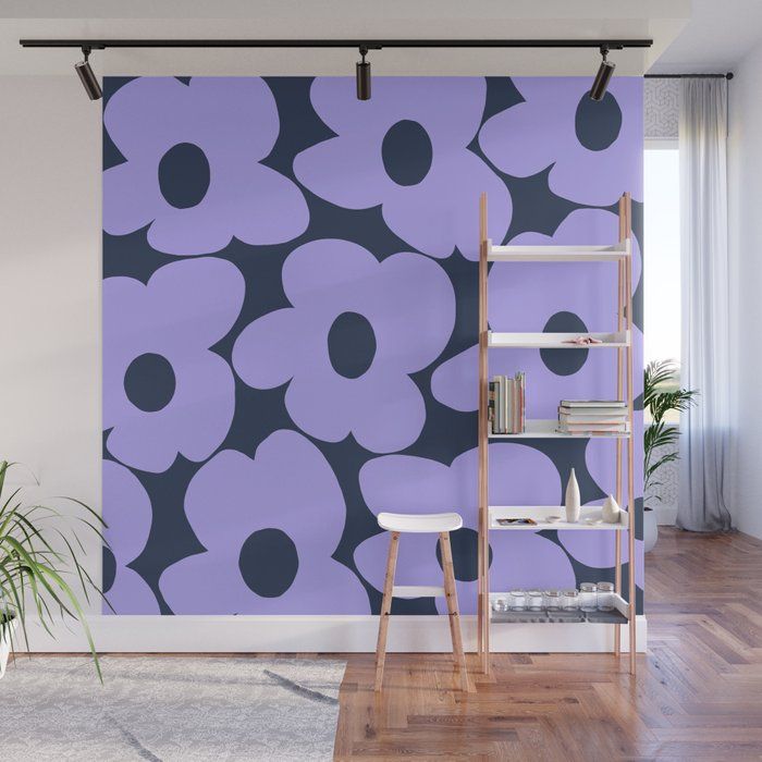 a purple and black flower wall mural in a living room with wooden floors, a book shelf, and potted plant