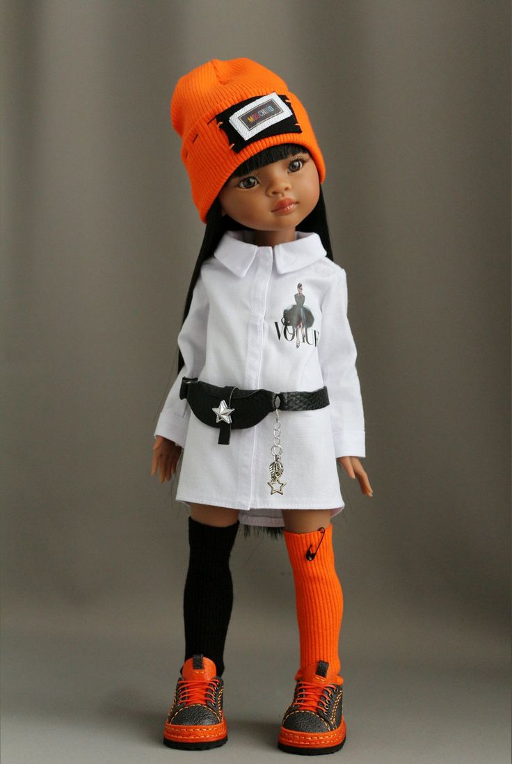 the doll is wearing an orange hat and white coat with black trim on it's legs