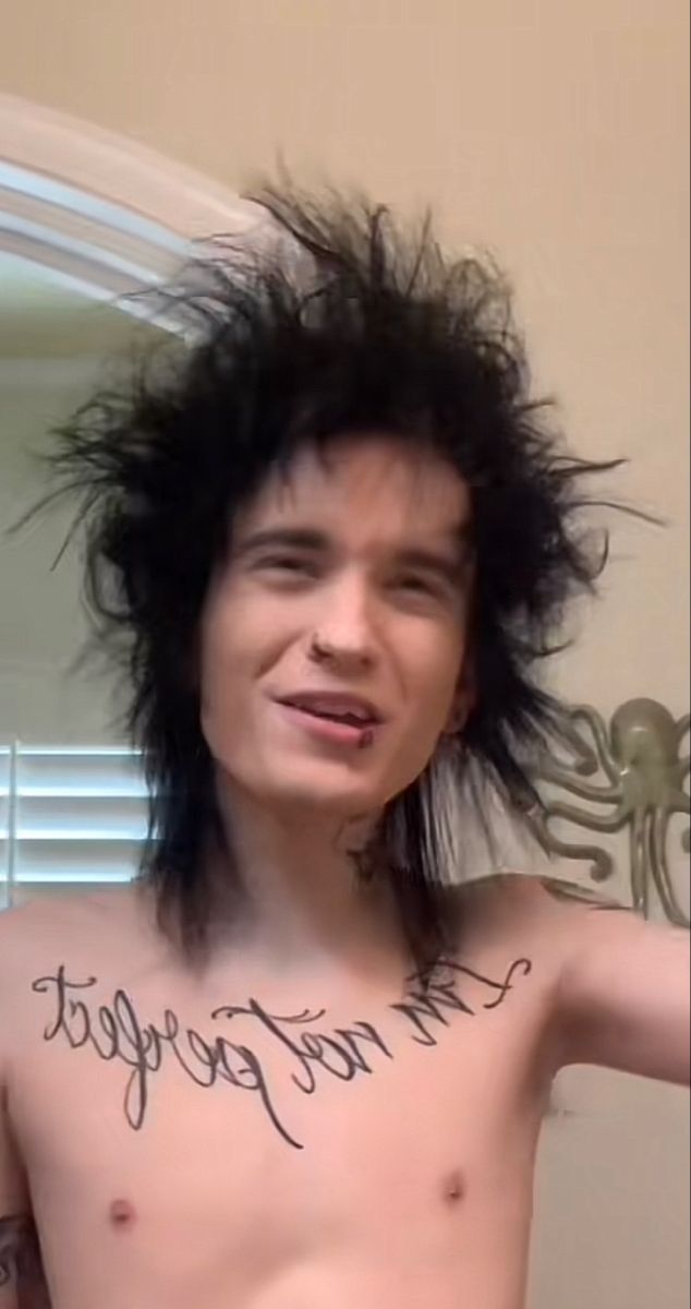 a shirtless man with his hair in the air and words written on his chest