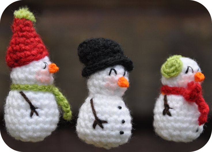 three crocheted snowmen wearing hats and scarves