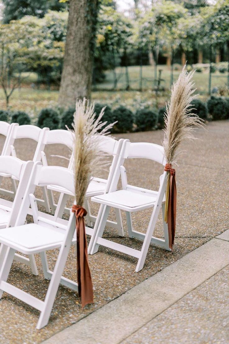 white folding chairs with brown ribbon tied to them are set up for an outdoor ceremony