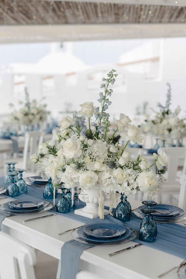 the table is set with blue and white plates, silverware, and vases