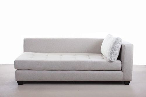 a white couch sitting on top of a floor next to a wall with a pillow