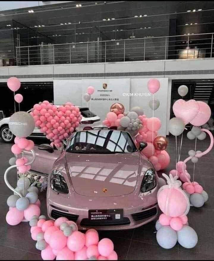 a car is parked in front of pink and silver balloons on the ground with other decorations around it