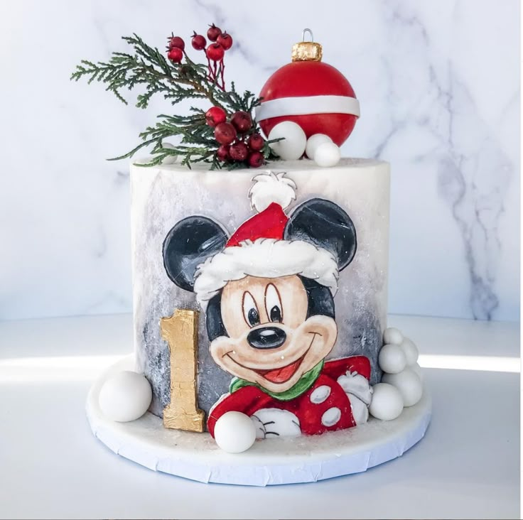 a decorated cake with a mickey mouse on it's side and a christmas ornament hanging from the top