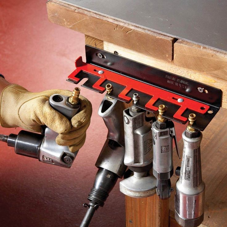 a person holding a drill and tool in front of a bench with tools attached to it