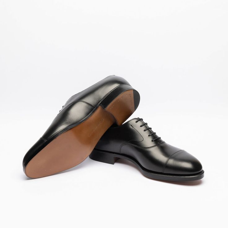 Black calf oxford shoe with stitched cap toe, double leather sole. Fitting F, last 202. Made in England Oxford Shoes With Rubber Sole And Plain Toe, Classic Oxfords With Round Toe, Classic Oxford Shoes For Derby With Leather Sole, Classic Oxford Shoes With Leather Sole For Derby, Goodyear Welted Oxford Dress Shoes With Almond Toe, Timeless Cap Toe Dress Shoes For Derby, Classic Goodyear Welted Plain Toe Oxfords, Office Oxfords With Goodyear Welt And Plain Toe, Timeless Plain Toe Oxford Shoes For Derby