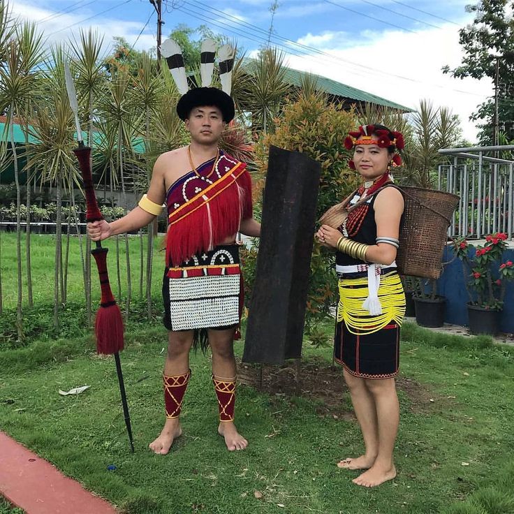 two people dressed in costumes standing next to each other on the grass with plants behind them