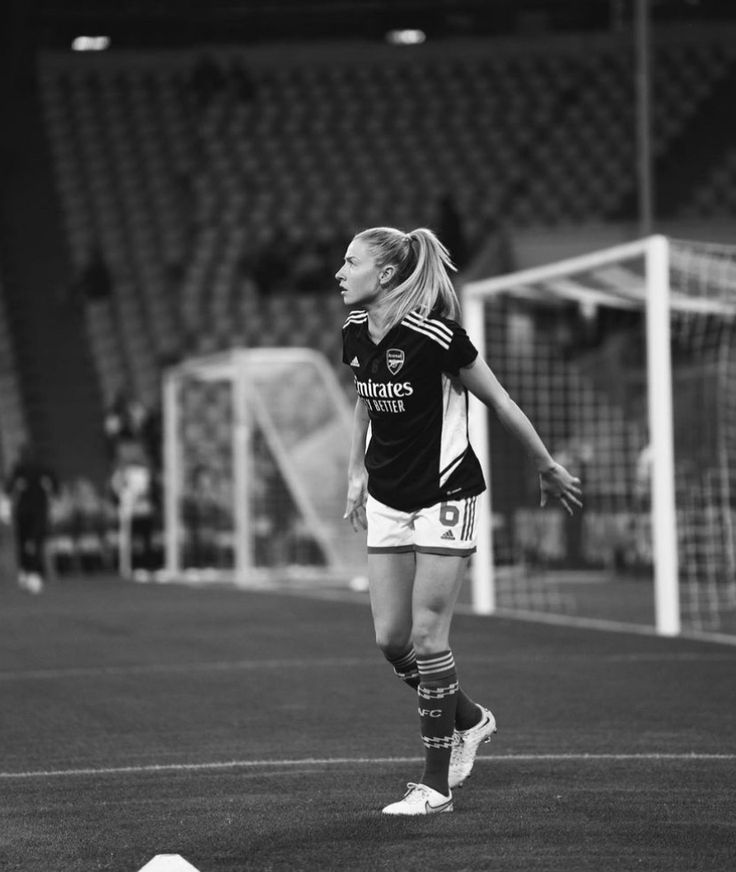 a female soccer player on the field during a game in black and white with people watching