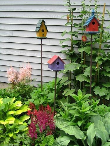 colorful bird houses are in the garden next to plants