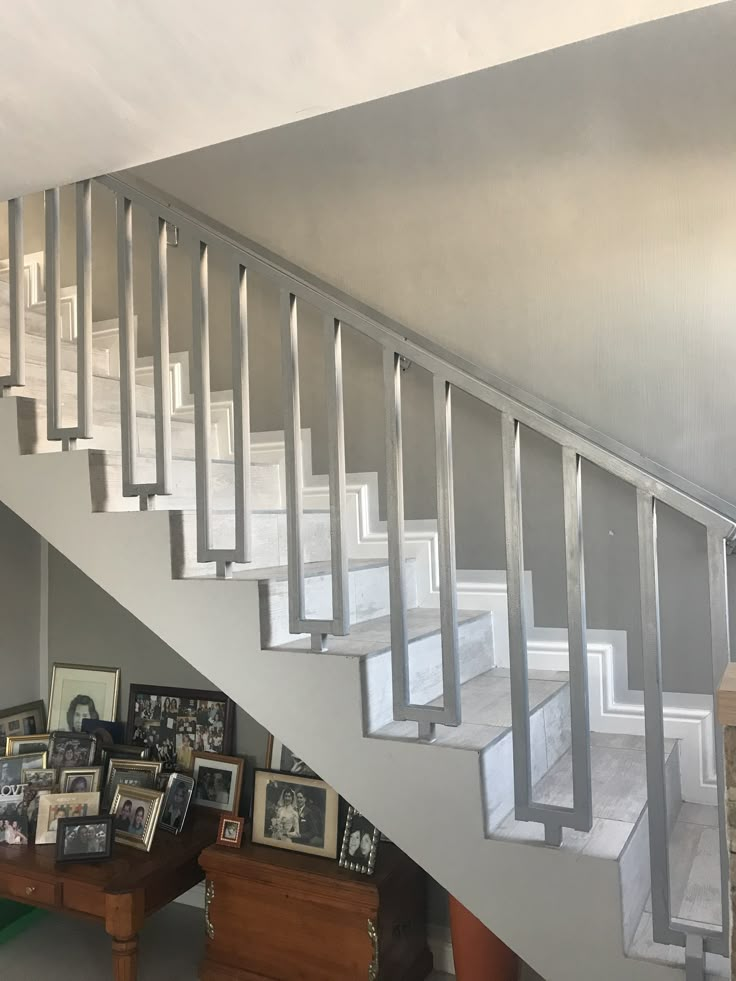 a stair case with pictures on the bottom, and framed photographs below it in an empty room