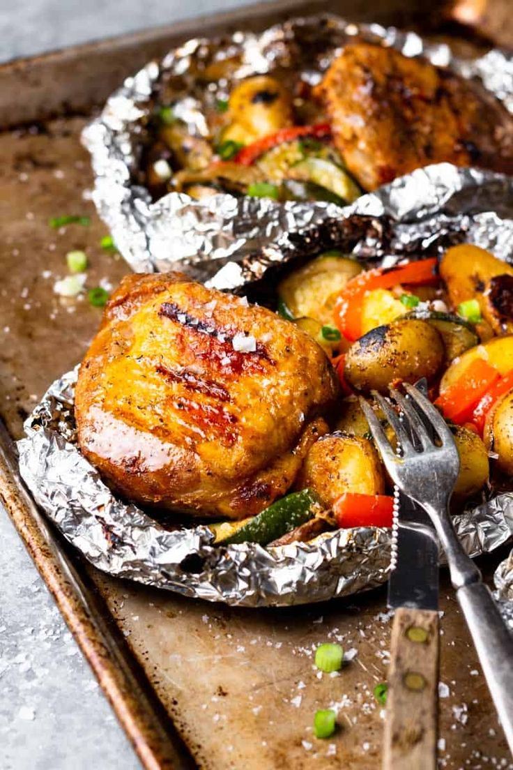 chicken and vegetables in foil on a tray with a fork, ready to be eaten