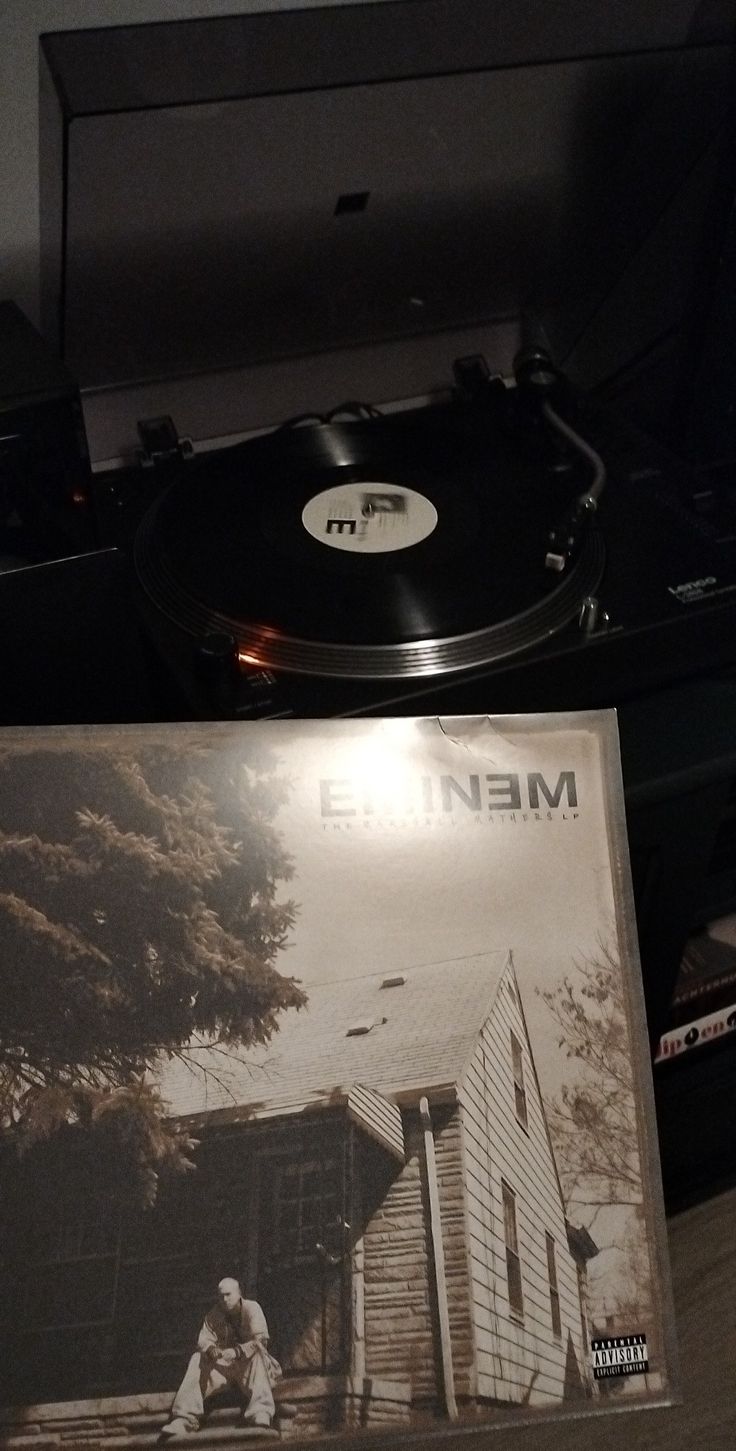 a record player sitting on top of a wooden table next to a vinyl album cover