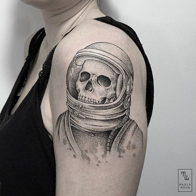 a woman with a skull in a space suit tattoo on her arm and shoulder is looking at the camera