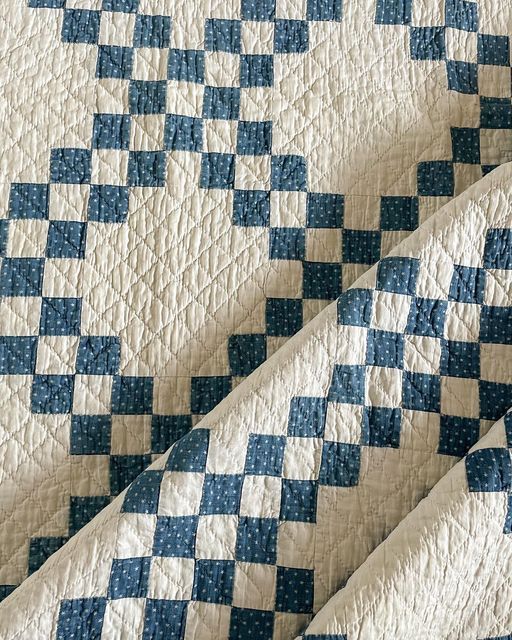 a blue and white checkered quilt on top of a tablecloth with an open end