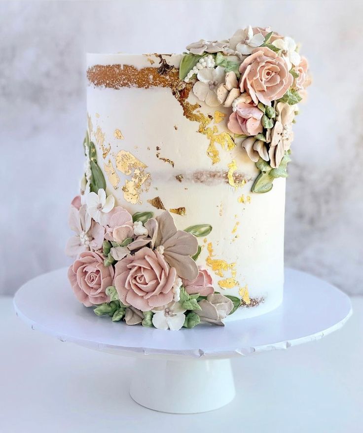 a white cake with flowers on it sitting on top of a table in front of a marble wall