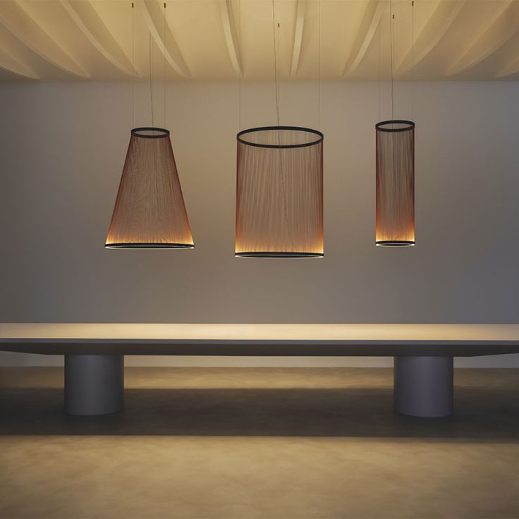 three lamps hanging from the ceiling above a table with a bench in front of it