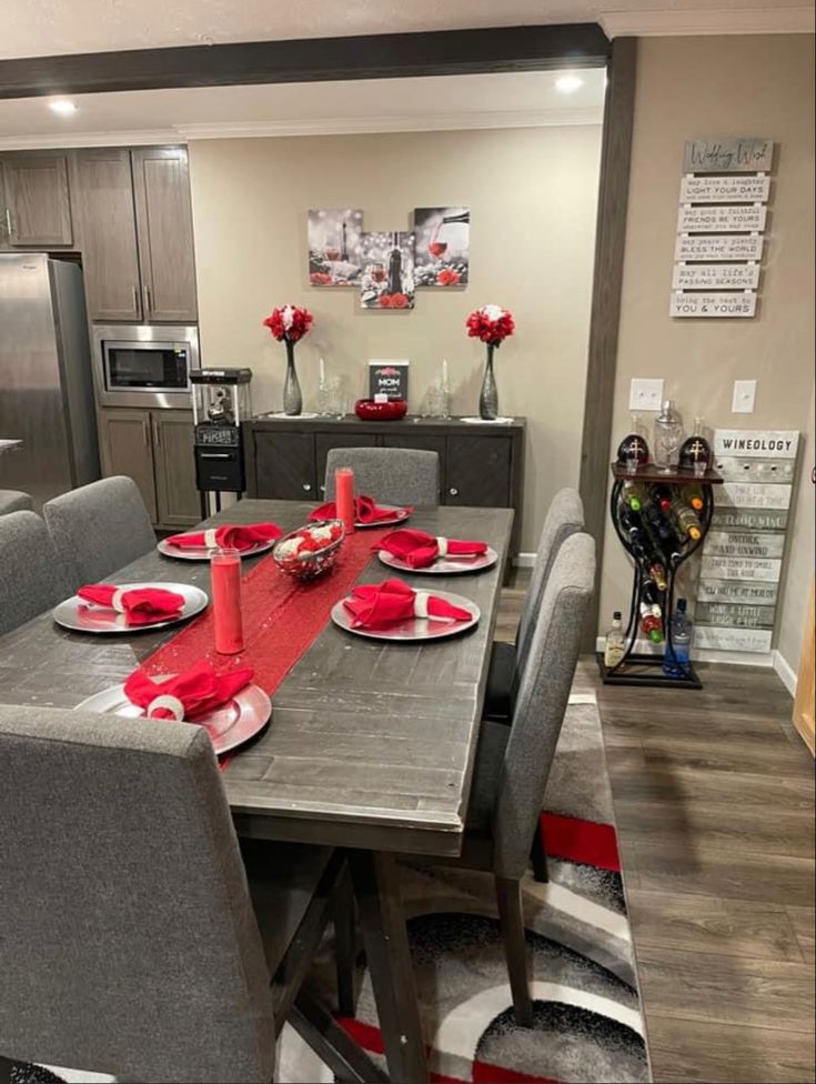 a dining room table set for four with red plates and place settings on the chairs