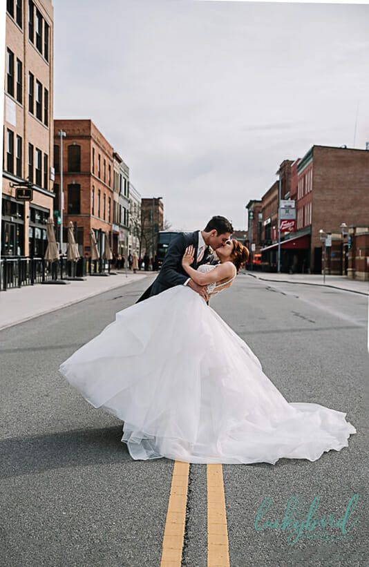 a bride and groom kissing in the middle of an empty street on their wedding day