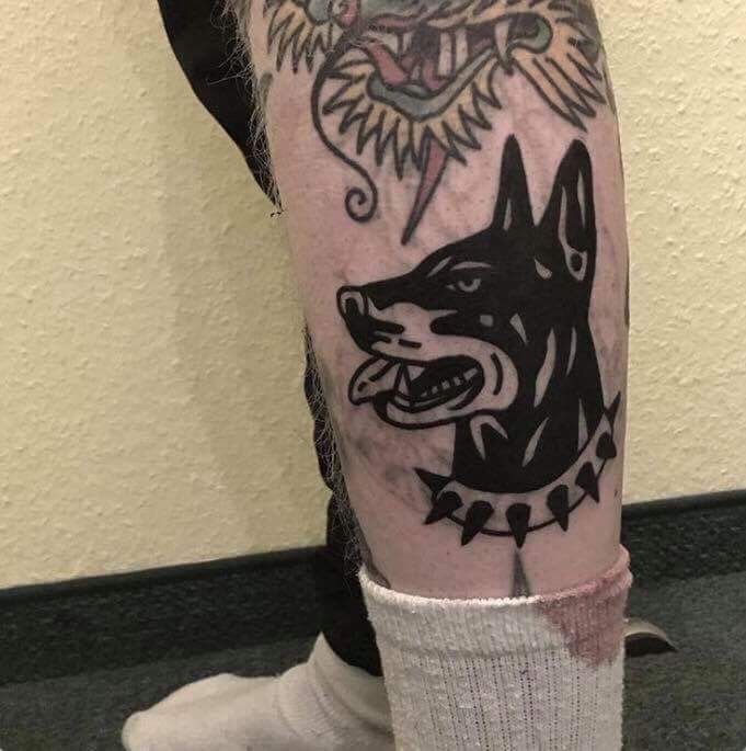 a man with a tattoo on his arm and leg is standing in front of a wall