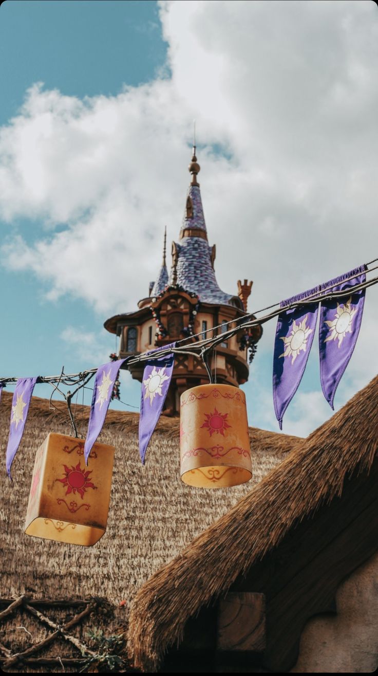 some paper bags hanging from a line on a house's thatched roof with a clock tower in the background