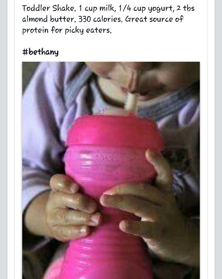 a young child drinking from a pink sippy cup