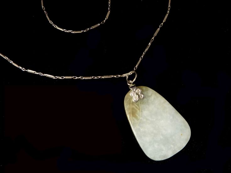 "A sliver of icy jade luxury with a fine, delicate silver chain.The pendant is an organic shape with a leaf carved at the top and side. The natural jade piece has a brownish cast at the top and a light turquoise-green-aqua collage of color which extends to the bottom.The chain is attached with a fine, flower shaped finding and a silver jump ring. The chain is delicate and detailed with an unusual bar and link design. The pendant is a pleasure to hold and is smooth and rounded. Very elegant! Dime Carved Jade Necklace In Silver, Carved Silver Jade Necklaces, Carved Silver Jade Necklace, Link Design, Green Aqua, Sterling Necklaces, Turquoise Green, Light Turquoise, Natural Jade