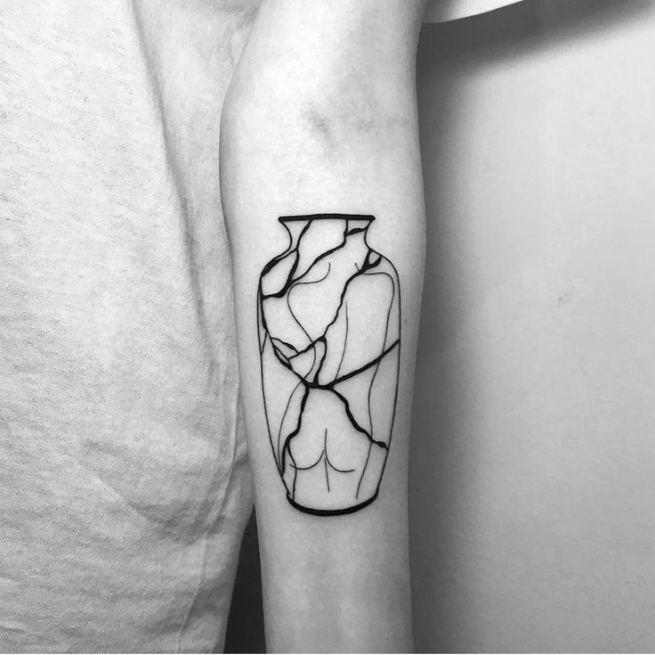 a black and white photo of a vase tattoo on the left inner arm, with lines running through it