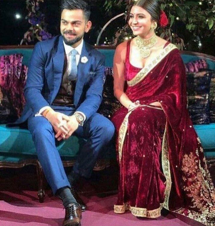 a man and woman sitting next to each other in front of a blue couch with red velvet