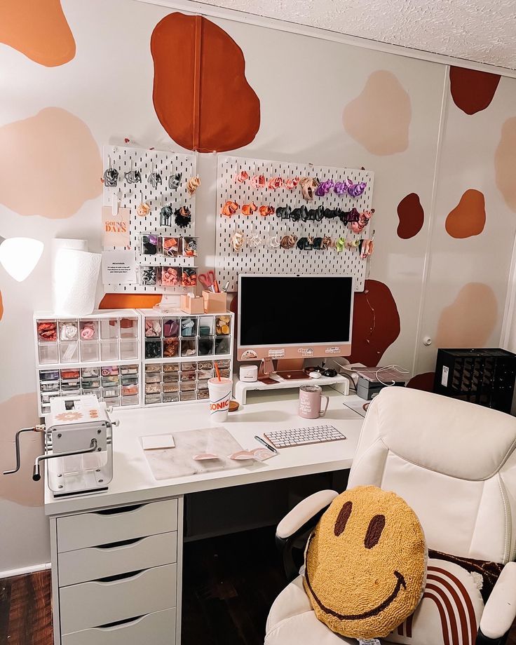 a white chair sitting in front of a computer desk with a smiley face pillow on it