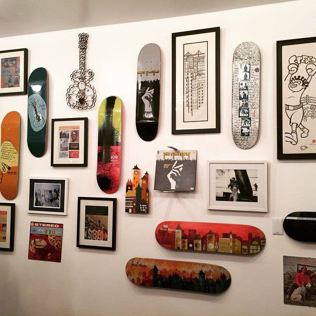 there are many skateboards mounted on the wall with pictures all over it and in front of them