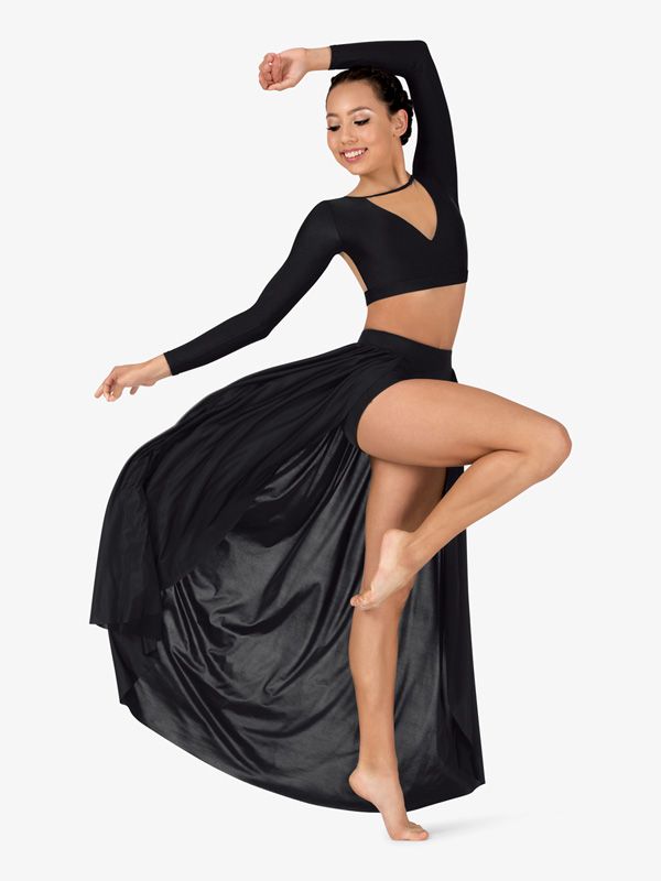 a woman in a black dress is dancing with her leg up and arms behind her head