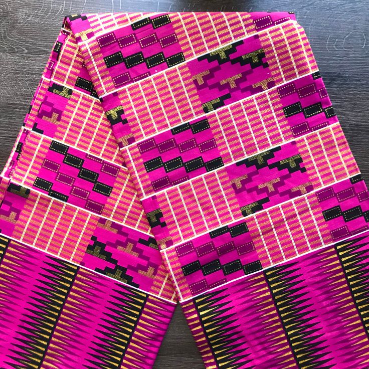 two pieces of pink and black fabric on a table top with a wooden surface in the background