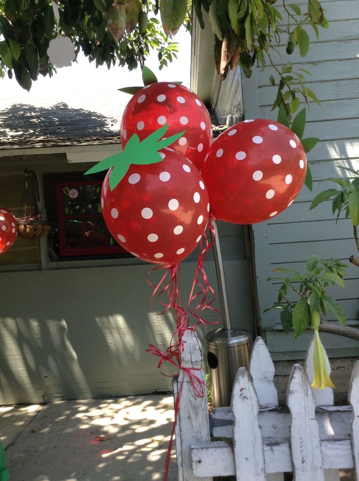 two red balloons with white polka dots on them are in front of a house and tree