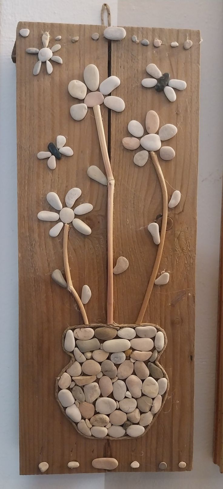 a wooden wall hanging with flowers and rocks in the shape of a flower pot on it