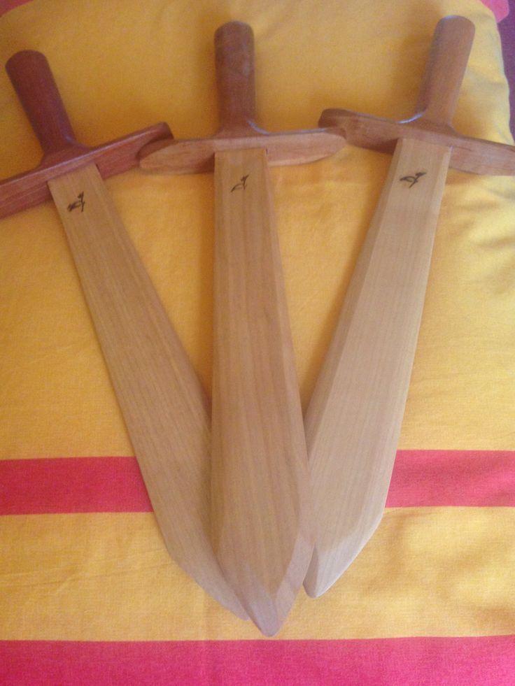 two wooden knives are laying on a yellow and pink striped bed spread with the handles down