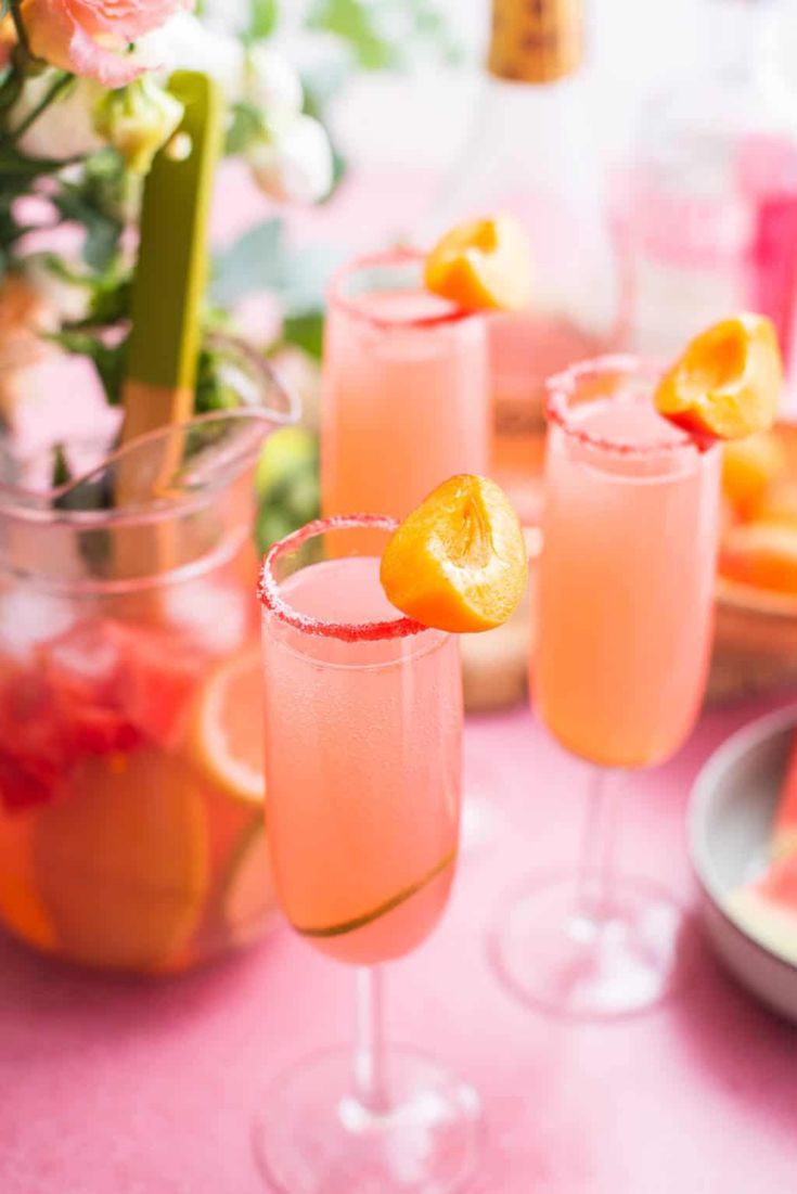 three glasses filled with pink lemonade sitting on top of a table