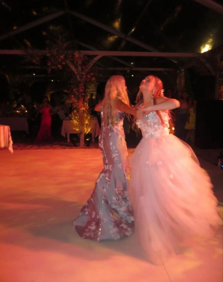 two women in dresses standing on a dance floor