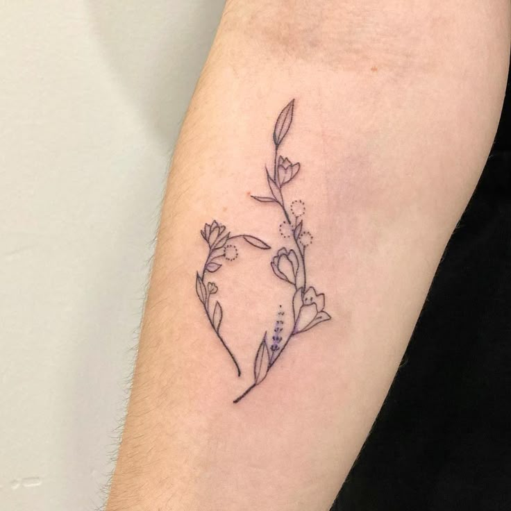 a small flower tattoo on the left arm