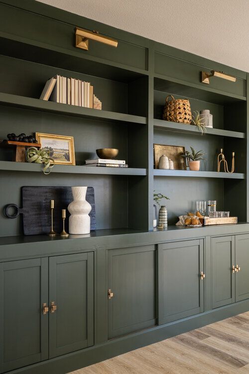 a green bookcase filled with lots of books and vases on top of it