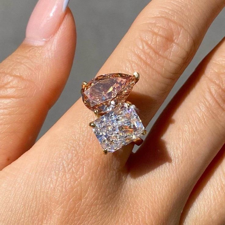 a woman's hand holding an engagement ring with two pear shaped diamonds on it