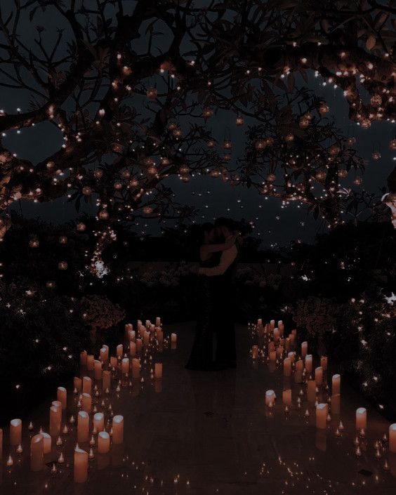 a couple standing under a tree filled with lit candles